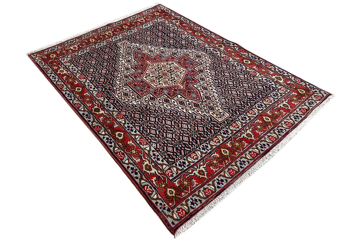 Hamadan rug at an angle with a fine tile pattern, red border, and dark background