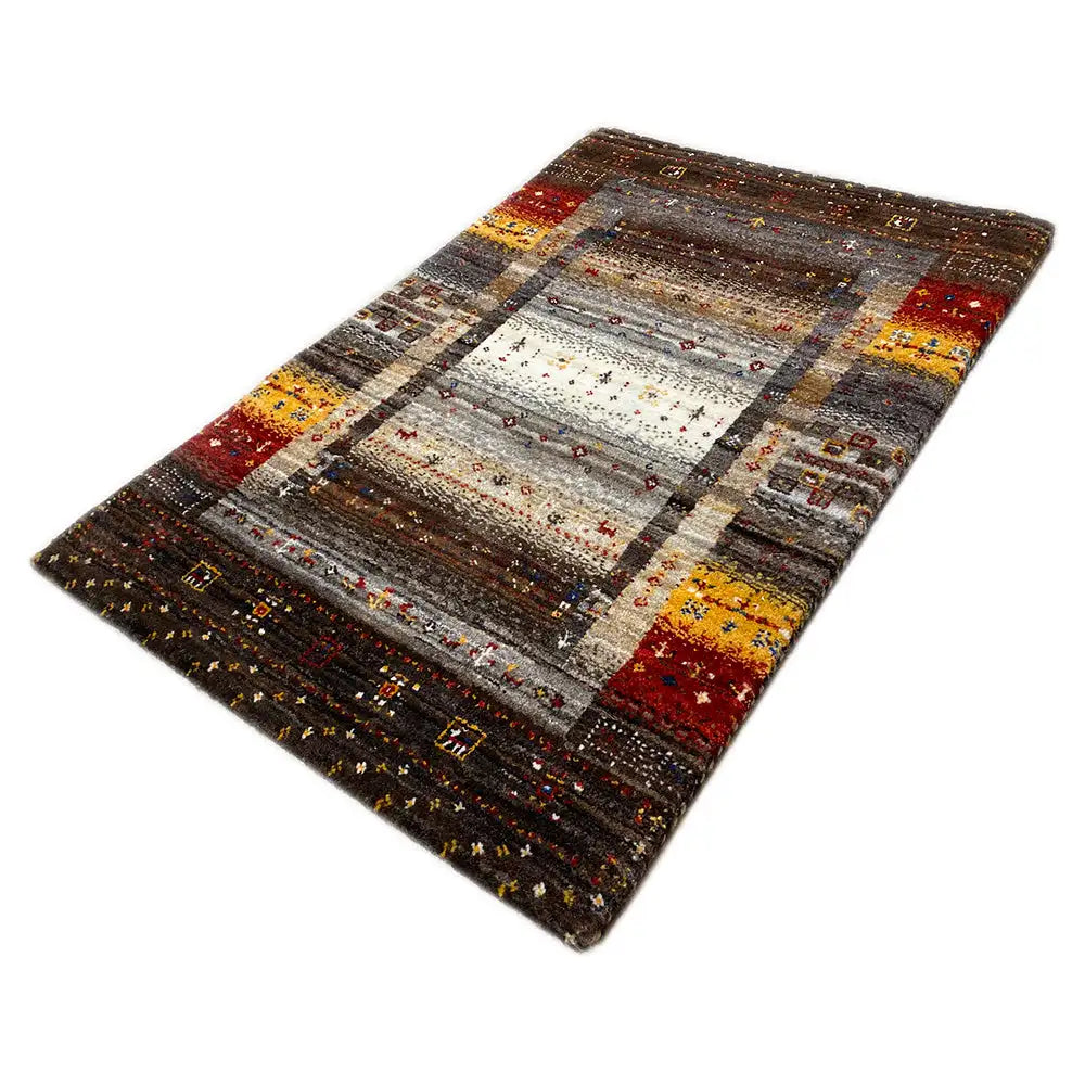 Gabbeh rug in angled view, mottled gray with a central medallion and yellow-red accents