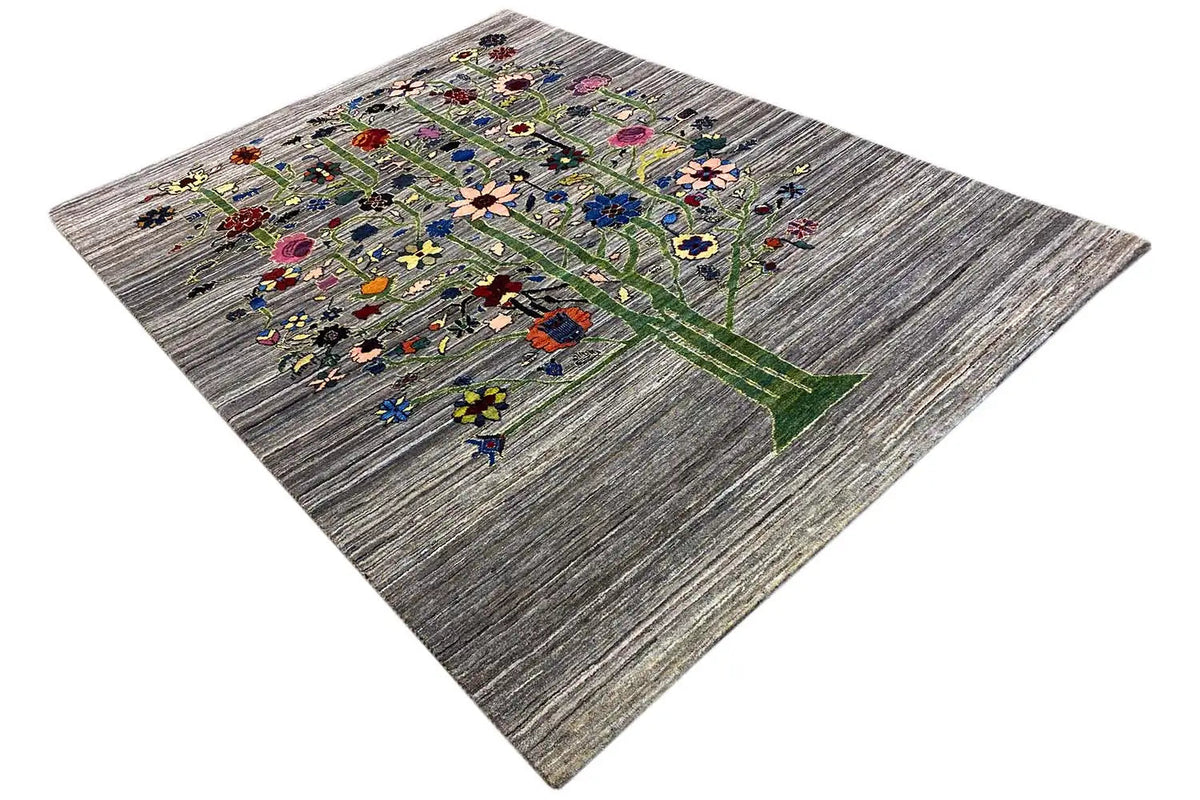Gabbeh-Lori rug at an angle, tree motifs and many small flowers on a gray background