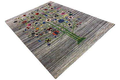 Gabbeh-Lori rug at an angle, tree motifs and many small flowers on a gray background