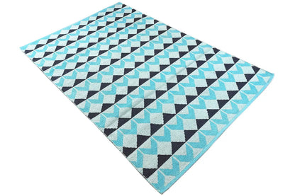 Rug in a diagonal zigzag design; turquoise, white and dark patterns on a light background