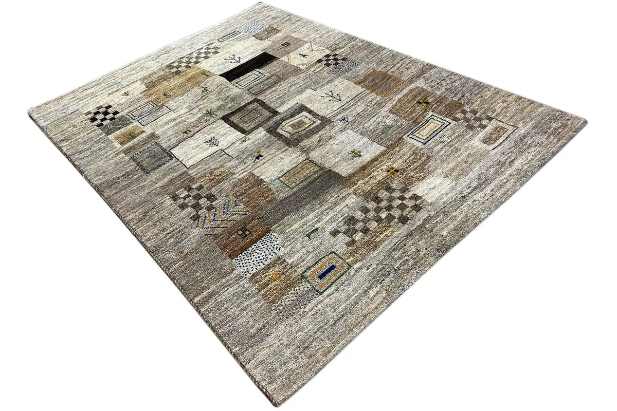 Gabbeh rug viewed from above at an angle: light beige pile with multicolored tiles and border lines