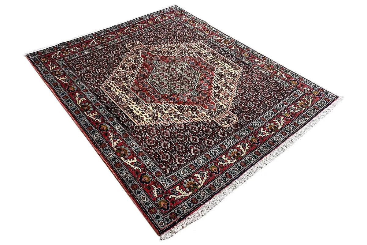 Hamadan rug at an angle with a geometric pattern and decorative border in red and blue