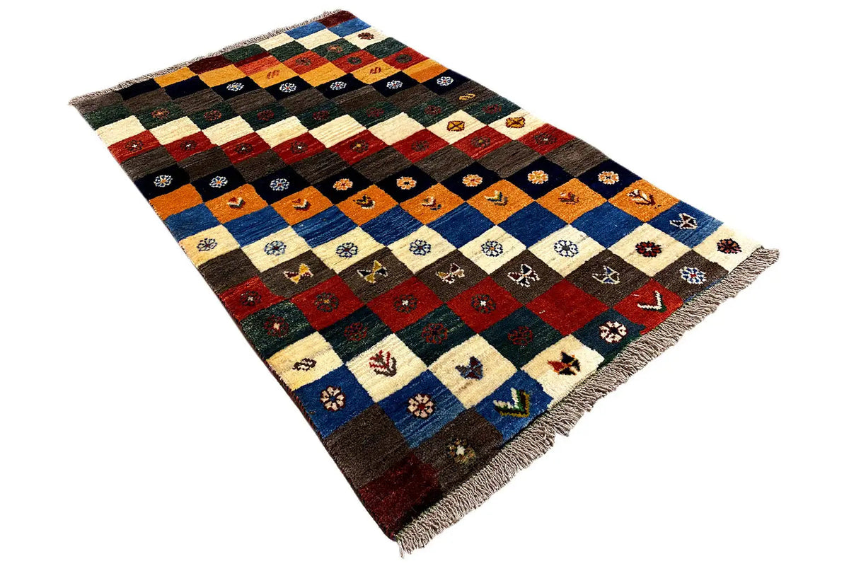 Gabbeh Lori rug at an angle with blue and red color blocks and decorative symbols, with fringes