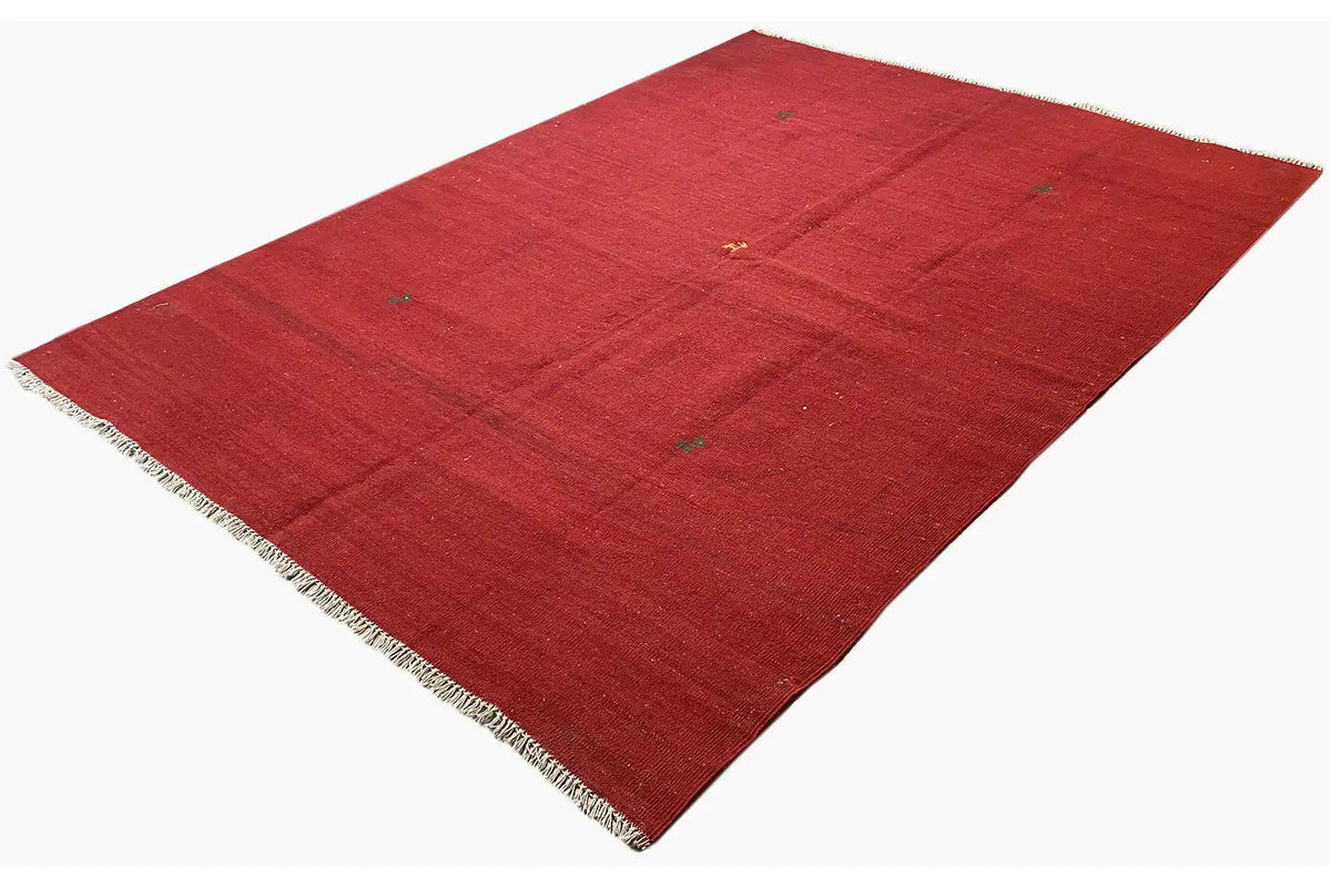 Kilim Qashqai rug in red, spread out at an angle with short fringes