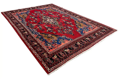 Oriental rug laid at an angle, red floral pattern with a blue decorative stripe and borders