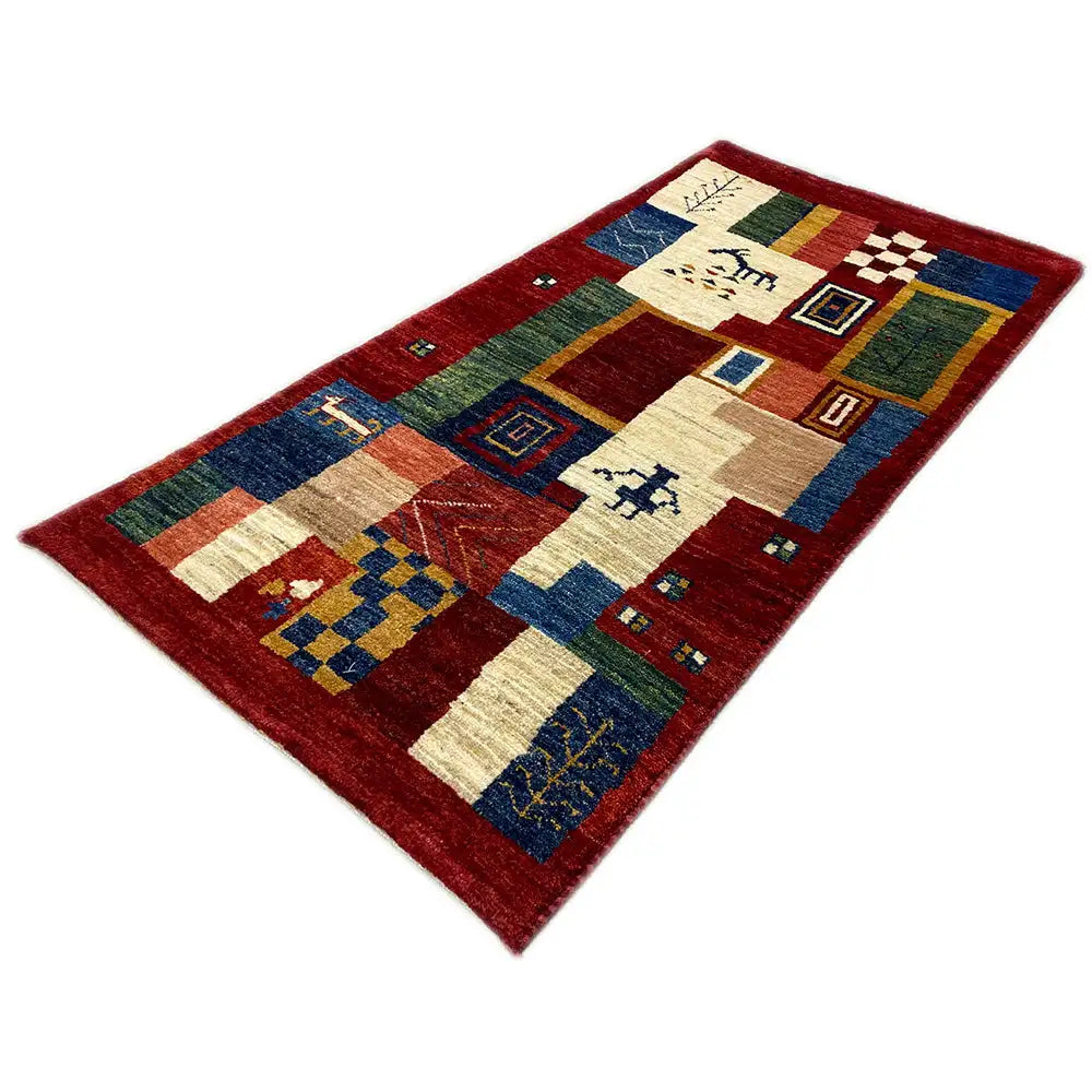 Gabbeh rug with geometric fields and decorative motifs in red, blue, and cream.
