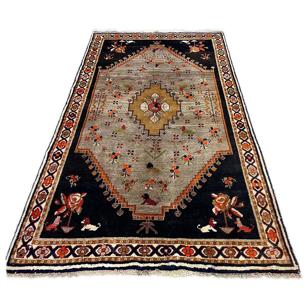 Rug with a black base and beige inner field, colorful floral motifs in the center