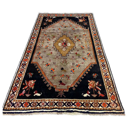 Rug with a black base and beige inner field, colorful floral motifs in the center