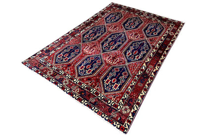 Oriental rug viewed from above at an angle: red field with blue ornamental medallions