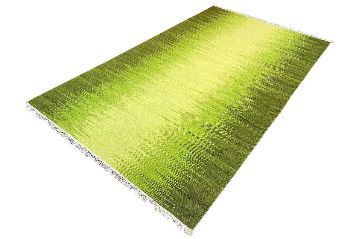 Large-scale green kilim rug with a textured woven pattern and fringes