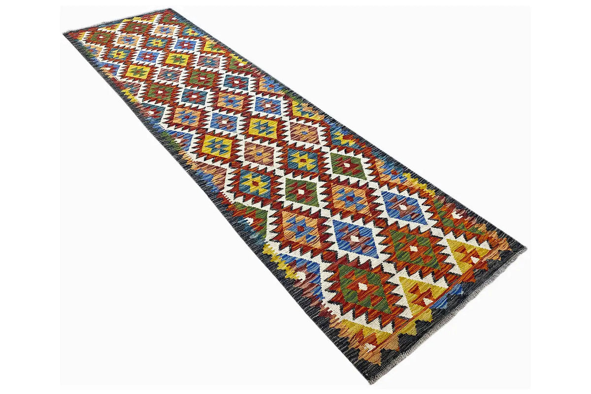 Kilim runner seen from above at an angle, with colorful diamonds, triangles, and a dark border