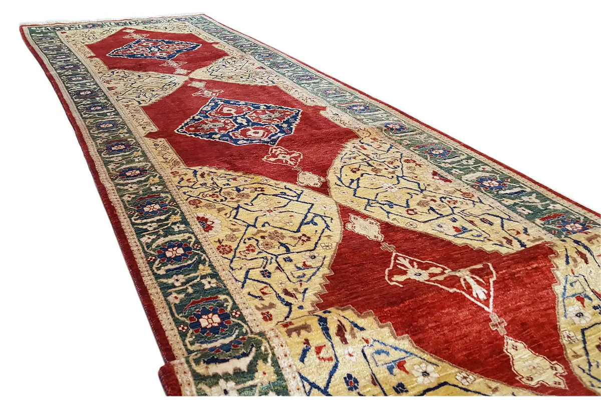 Oriental rug at an angle: red patterned field with a blue border and decorative motifs