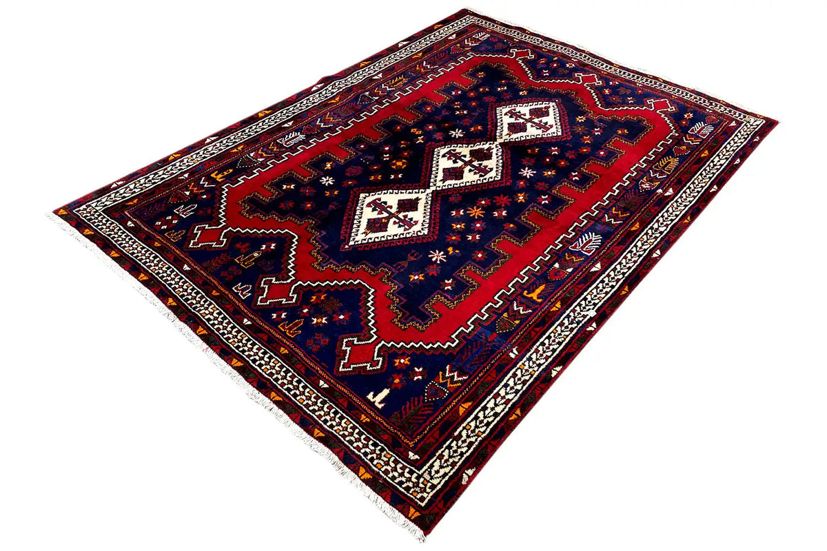 Oriental rug laid at an angle with a blue background, red medallion, and white ornamental border.