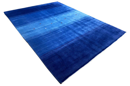 Blue rug at an angle with an even pile, color stripes, and fine colorful accents
