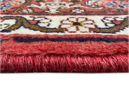Rug edge with red fringe and a multicolored woven pattern along the border
