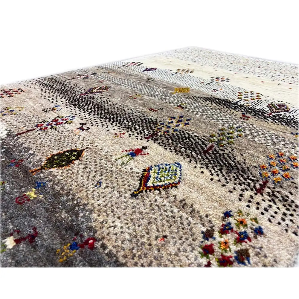 Gabbeh rug detail view: beige pile with colorful, embroidery-like symbols