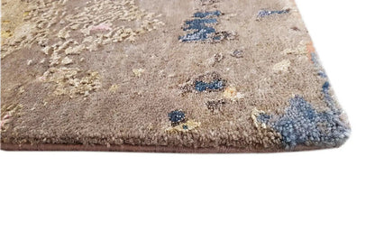 Rug corner with short, dense pile and abstract color patches in beige, blue, and red