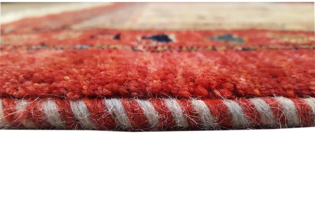 Edge fringes of an Oriental rug with a red pile and a dark decorative line along the hem.