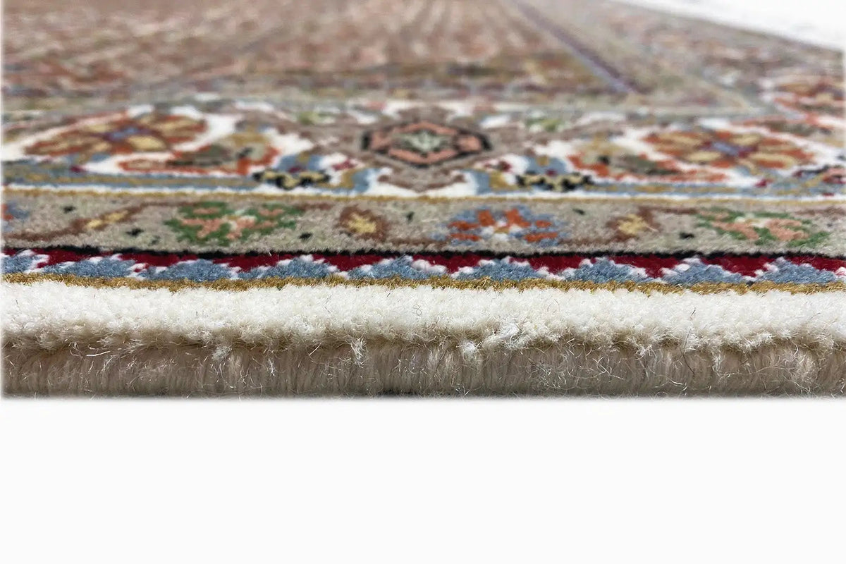 Rug edge with multicolored border design and dense white fringe