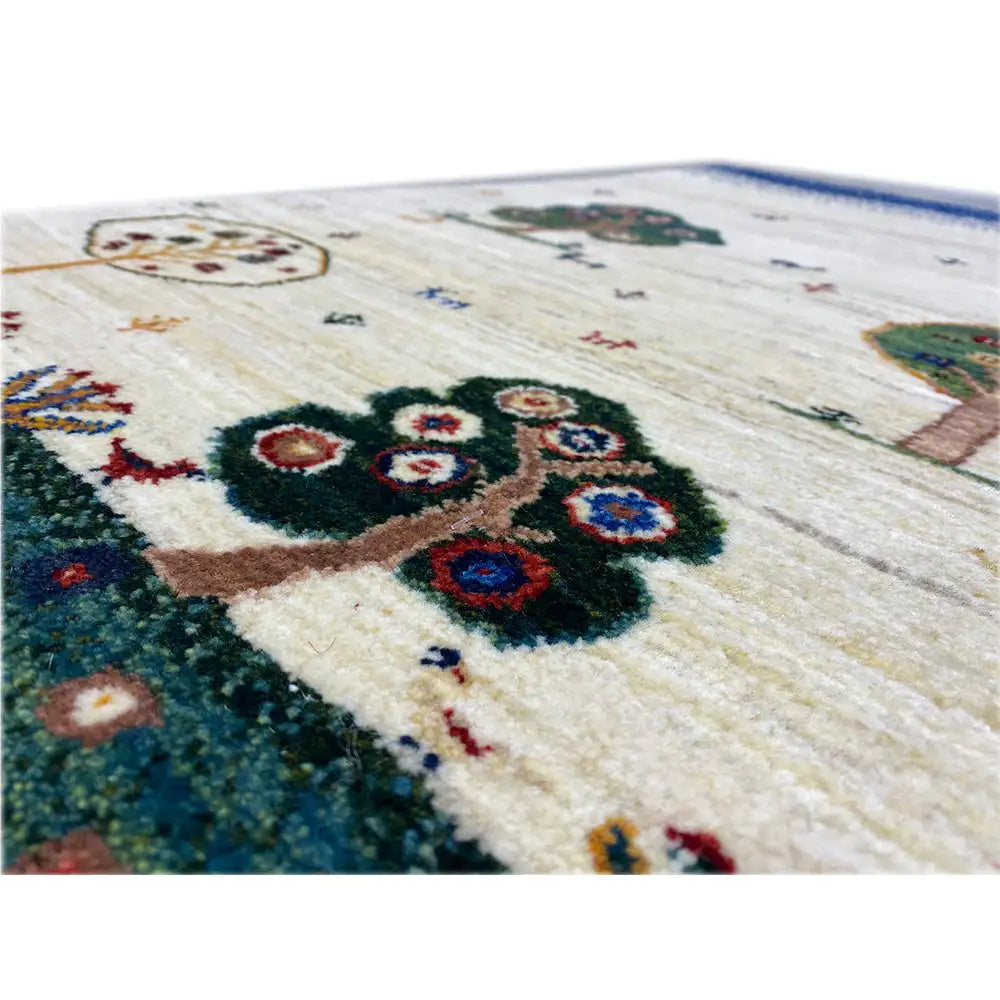 Gabbeh rug detail: multicolored tree ornament on a beige pile, dark green border area.