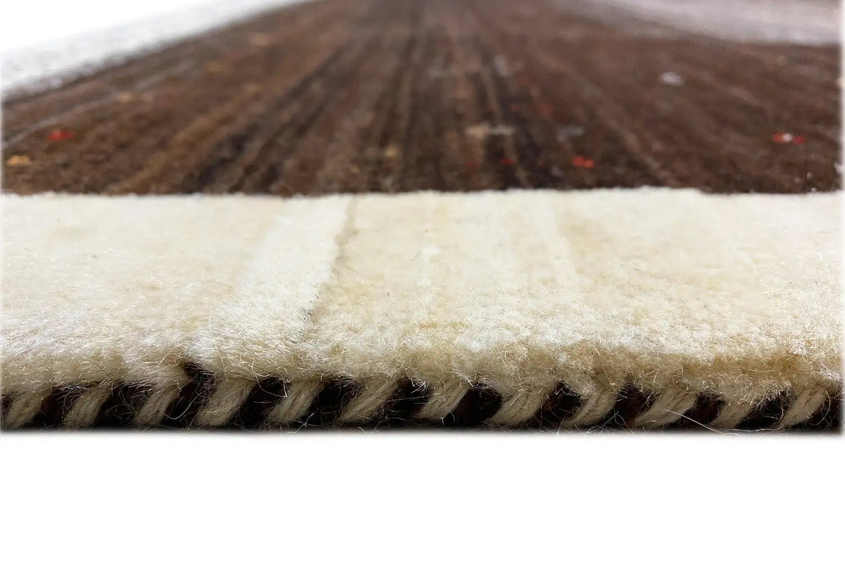 Close-up of a Gabbeh rug: light edge and short fringe, dark pile