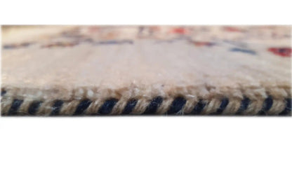 Rug edge with fringe and woven pattern in beige, dark blue, and red.