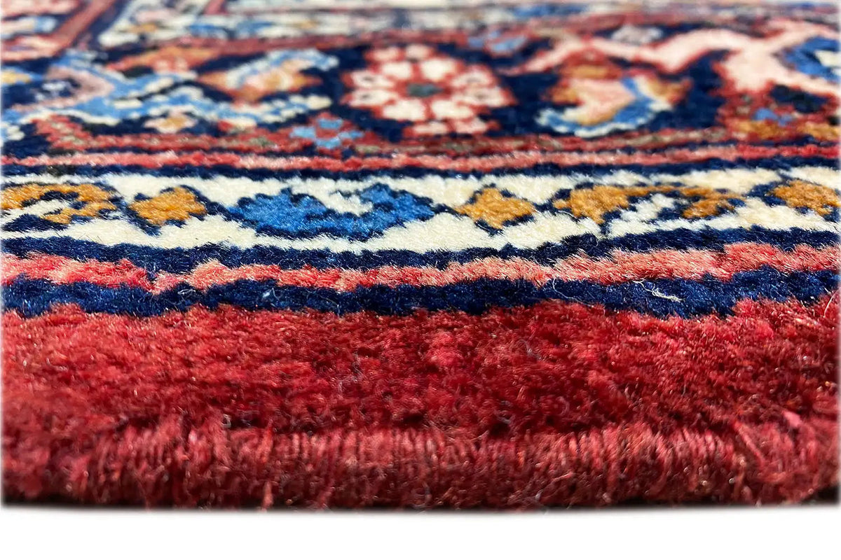 Carpet detail: red pile and fringes with a visible ornamental pattern