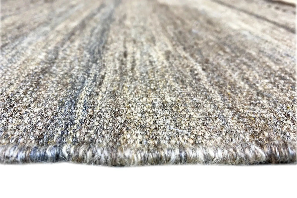 Kilim rug close-up: short woven pile texture in gray and beige tones, with fringes