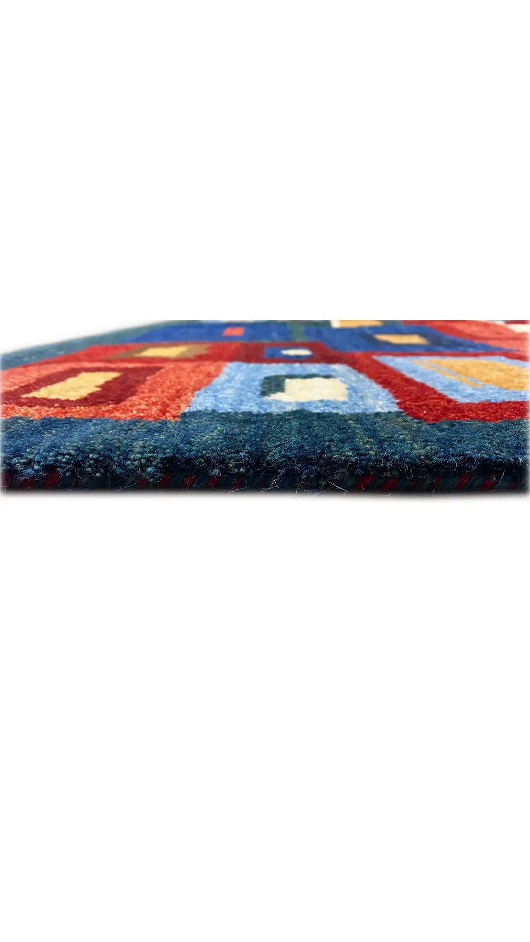 Gabbeh rug, edge view: broad bands of color in blue, red, beige, and green.