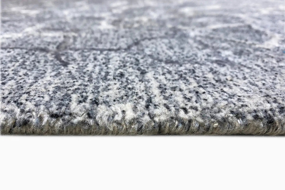 Hand-tufted rug, close-up: gray pile with a heathered surface and woven edge
