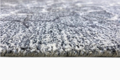 Hand-tufted rug, close-up: gray pile with a heathered surface and woven edge