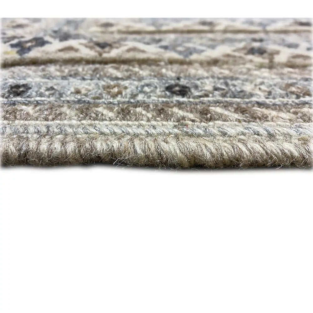 Close-up of pile height: blue-gray carpet with beige and dark raised details, short pile