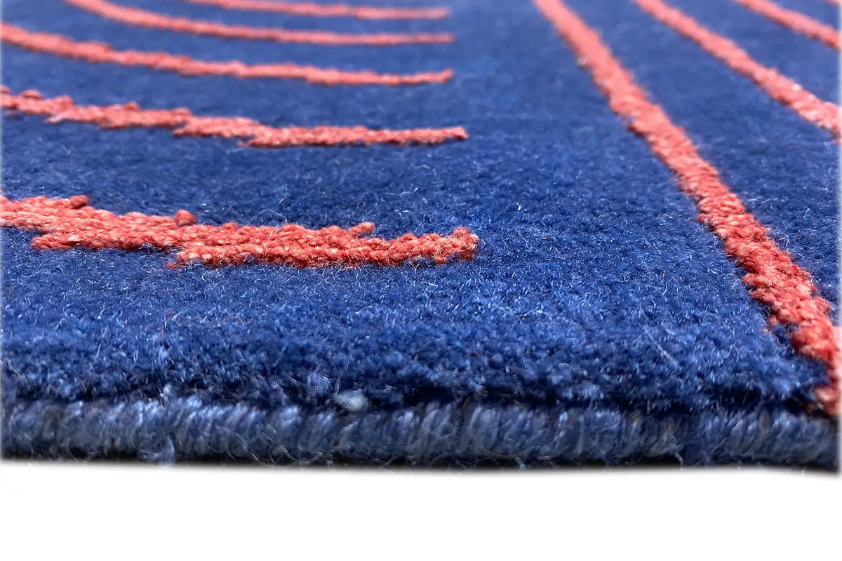 Carpet edge with blue pile, orange stitching, and a fine wave texture