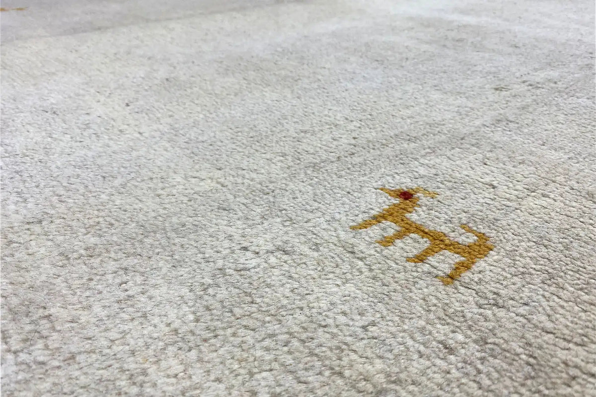 Close-up of the rug: light pile surface with a brown animal motif and fine texture