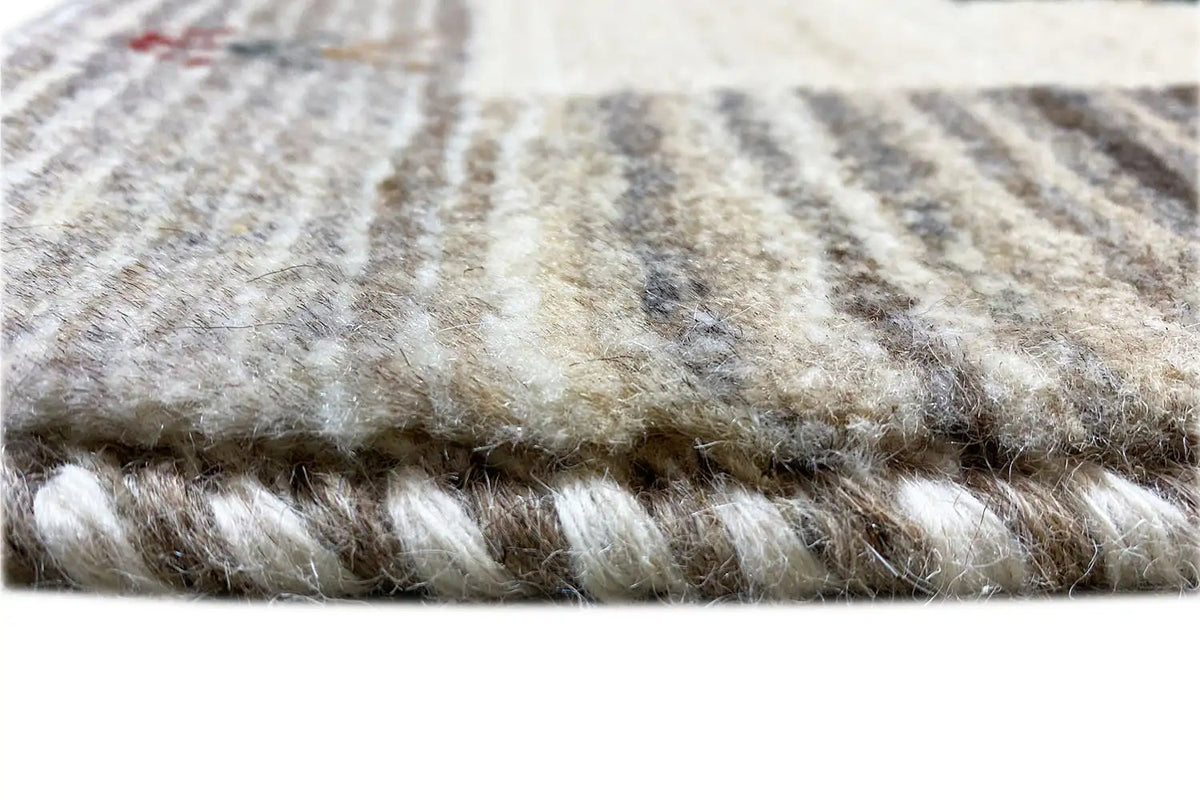 Gabbeh rug: close-up of the pile height with cream and gray fibers at the edge