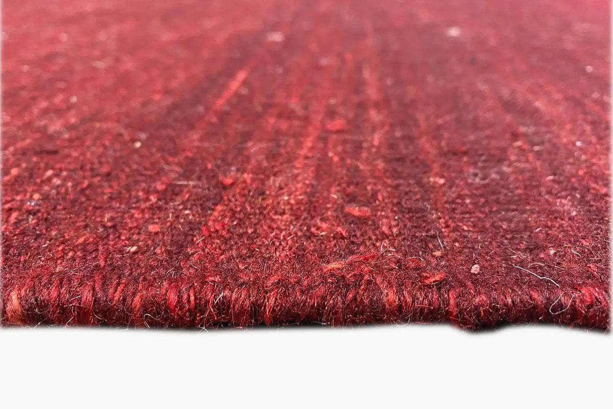 Close-up of the edge of a red kilim rug with dense fringes and a woven texture