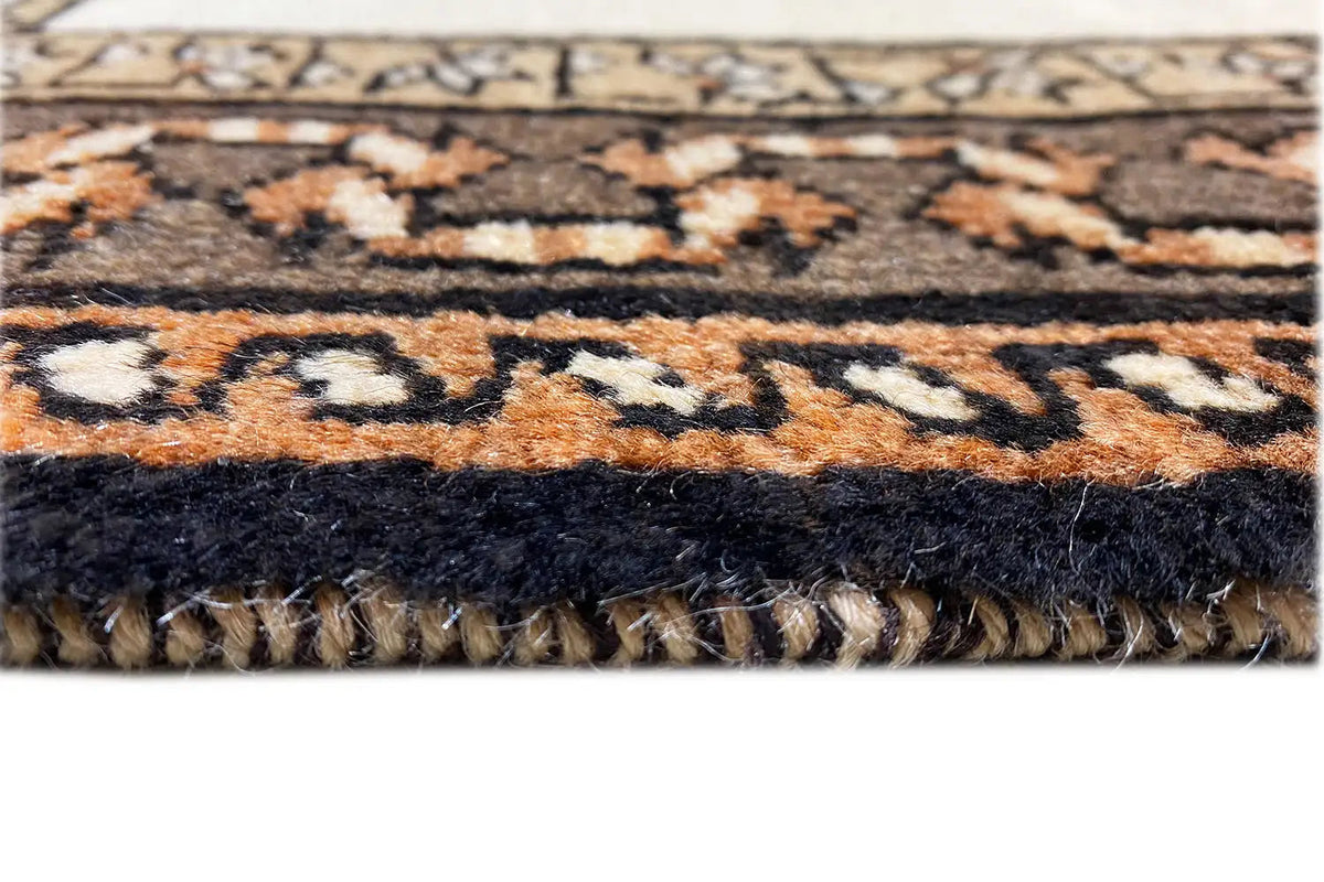Rug edge with tassels and a patterned border in brown, black, and beige.