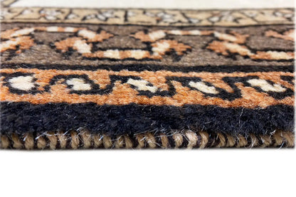 Rug edge with tassels and a patterned border in brown, black, and beige.
