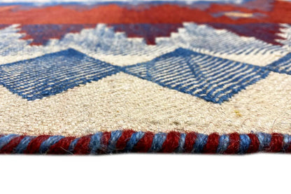 Rug edge with fringes and a woven blue-and-cream pattern on a cream background