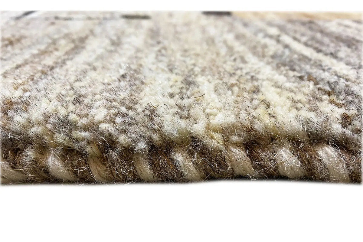 Rug edge with a dense, mottled pile texture in light beige and gray