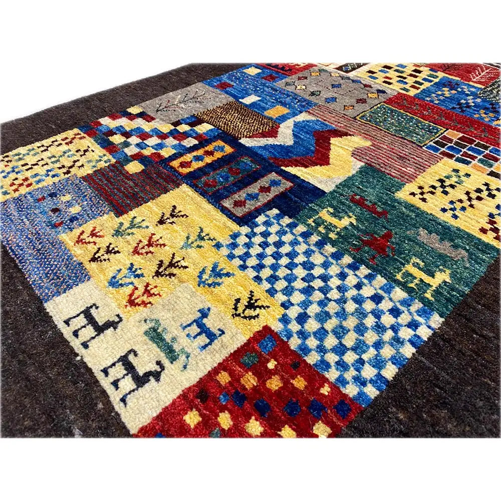 Close-up of a Gabbeh rug: colorful patchwork with zigzag and animal motifs, dark background