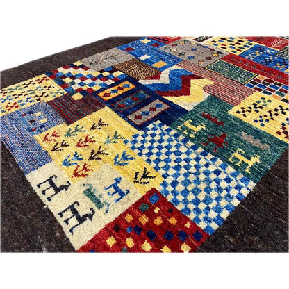 Close-up of a Gabbeh rug: colorful patchwork with zigzag and animal motifs, dark background