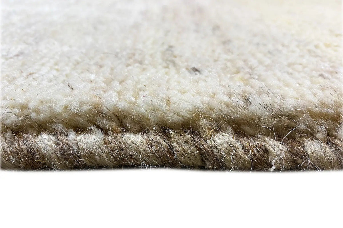 Close-up of a Gabbeh rug: dense beige pile with brown nuances at the edge