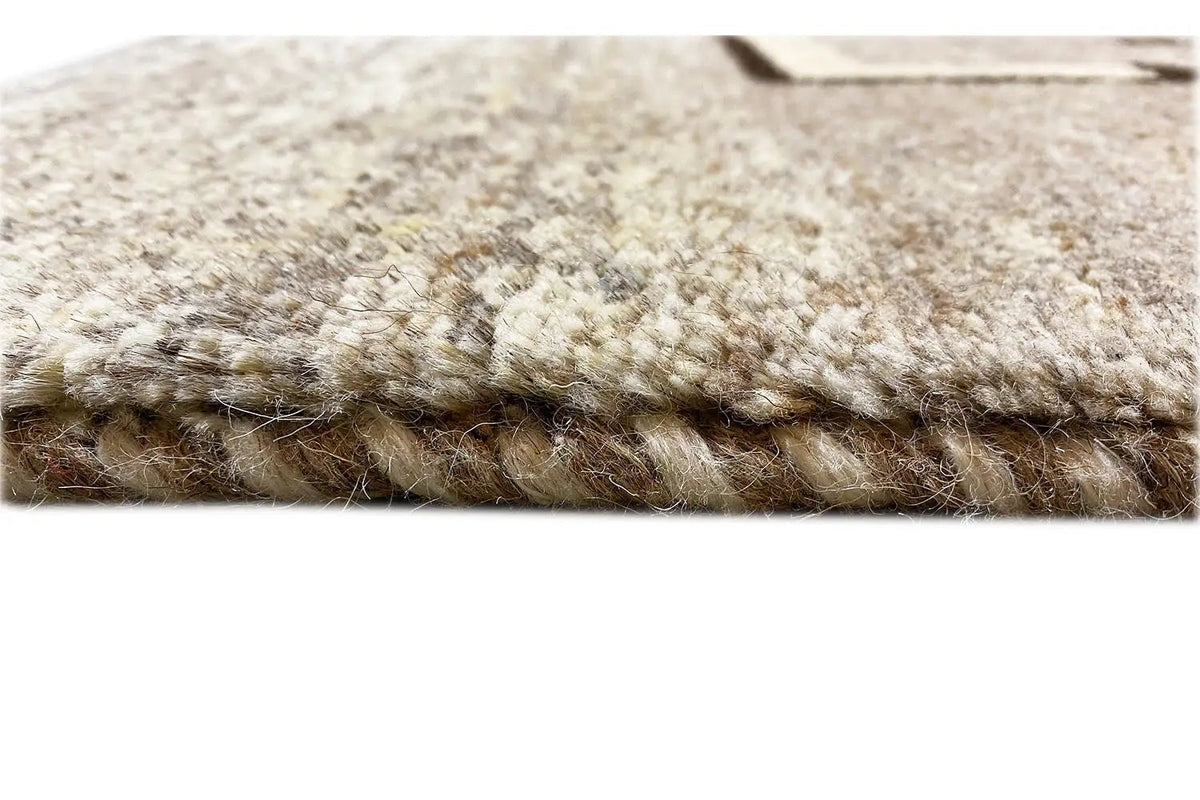 Close-up of the Gabbeh rug: dense pile and felted edge, light gray/cream
