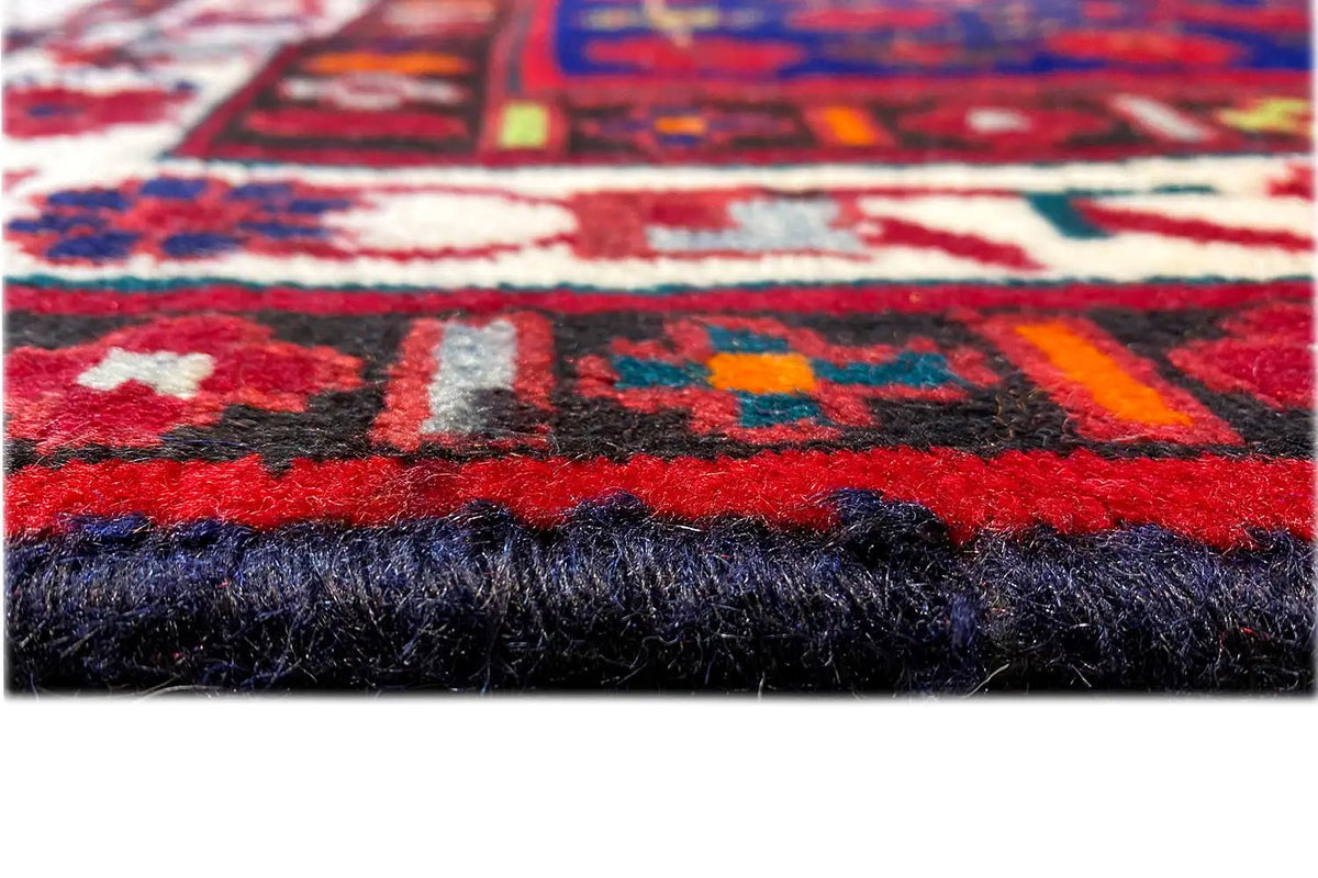 Carpet detail with red pattern, dark pile edge, and fringe strands