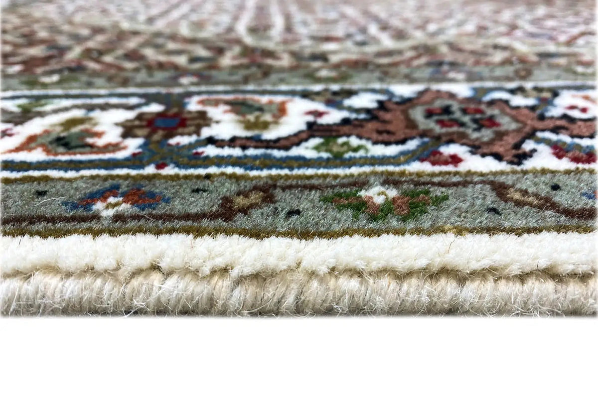 Indo Tabriz rug: close-up with fringes and a multicolored border pattern
