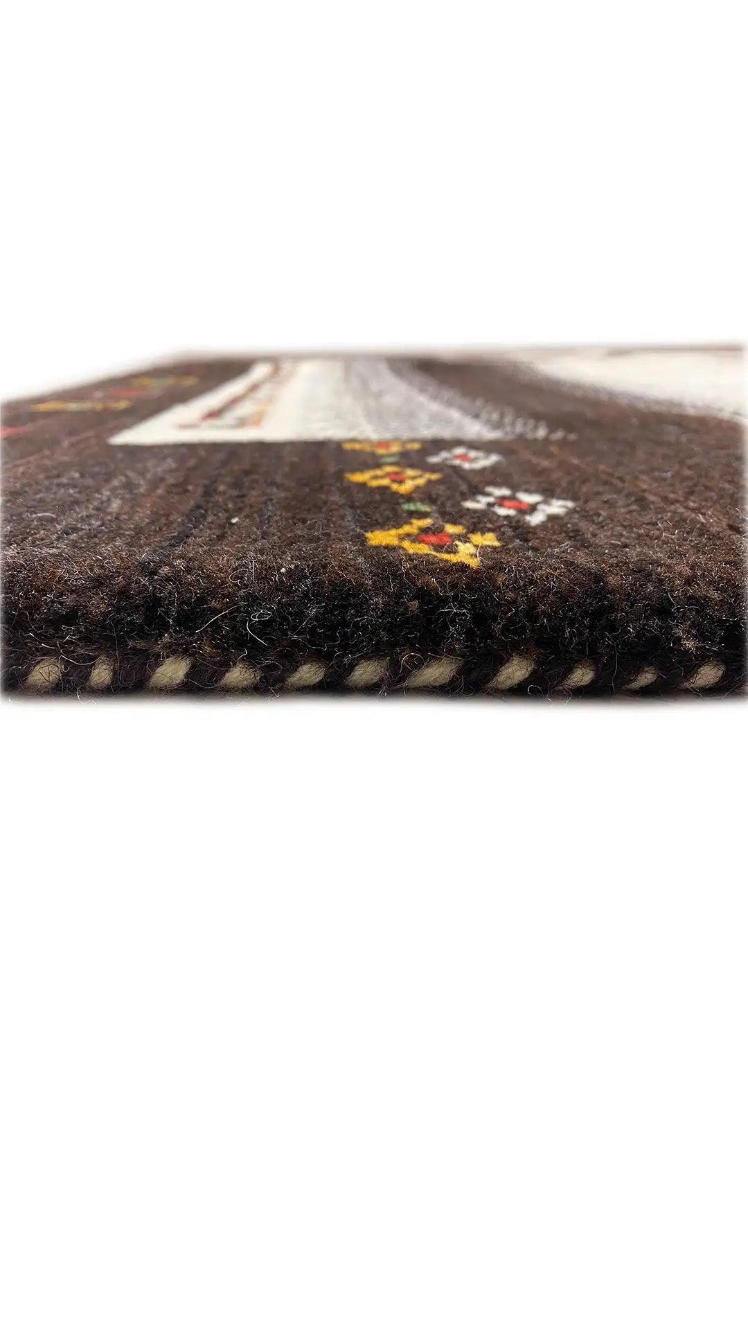 Gabbeh rug edge view: dark pile, beige stripe, and yellow-red motifs