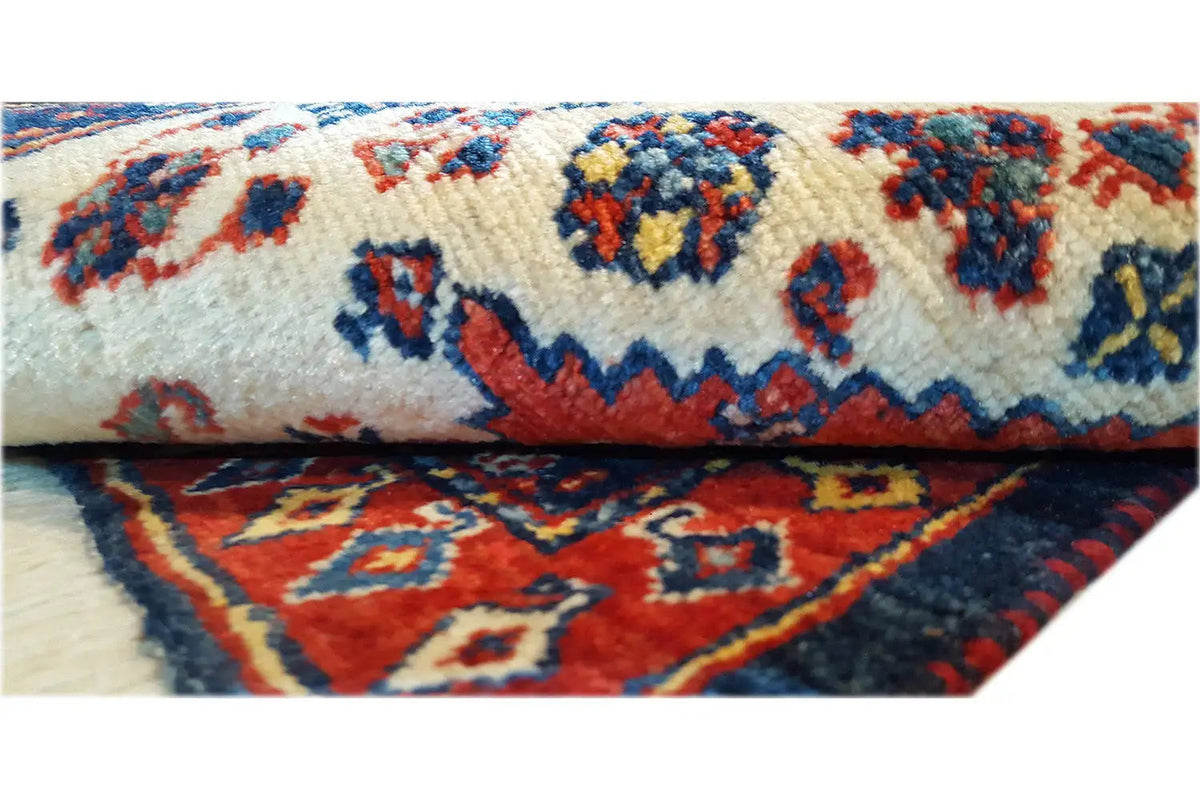 Oriental rug with a cream-colored pattern and a blue-and-red patterned border, close-up