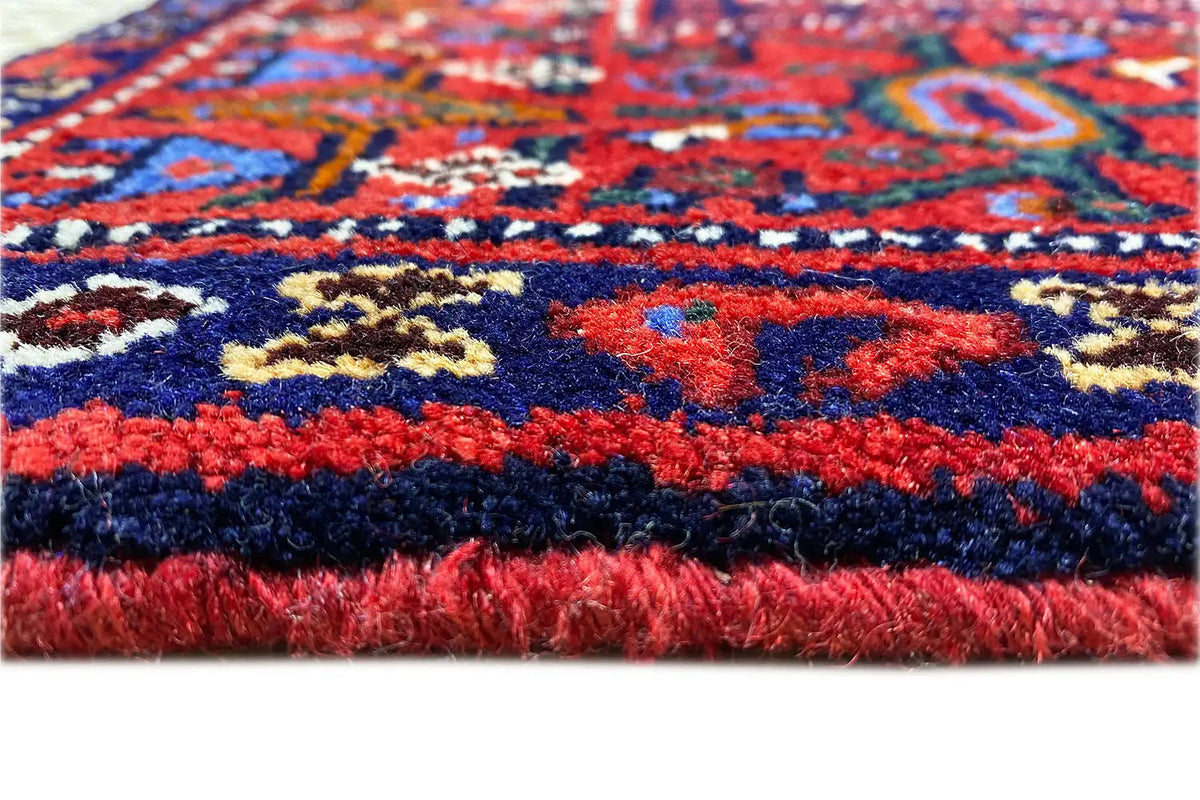 Carpet detail: colorful relief weaving with red, blue, and yellow ornamentation at the pile edge.